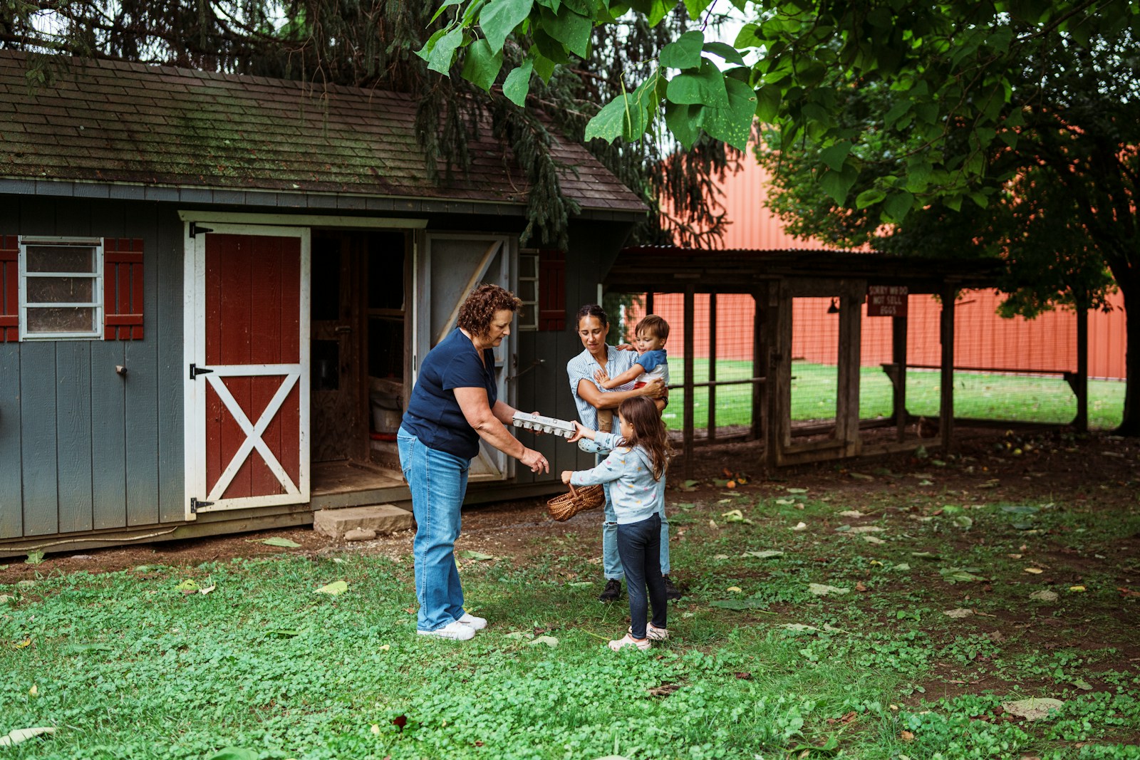 Family interacts with a woman near a shed.